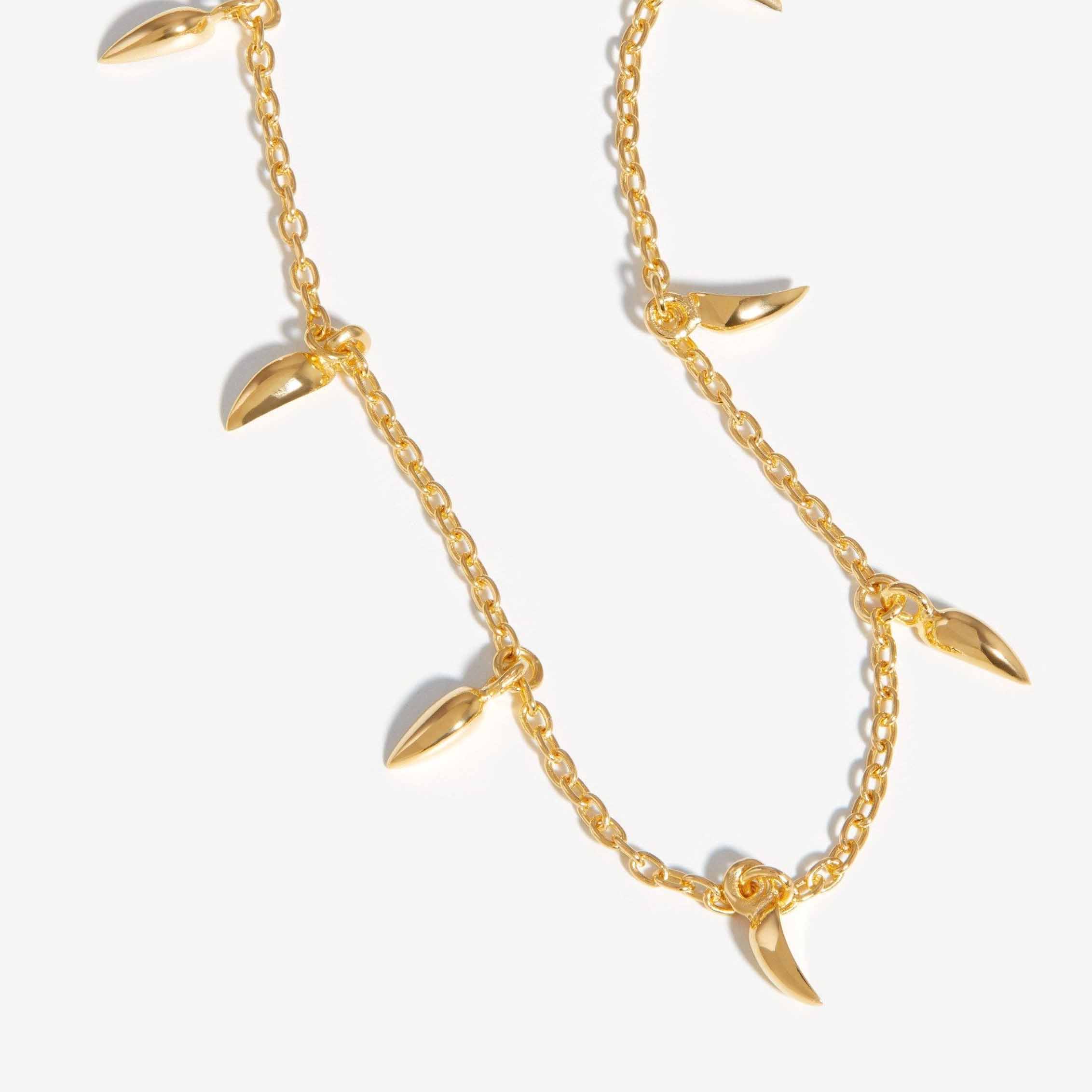 Wykonane na zamówienie naszyjniki typu choker z mini kłami, pokryte 18-karatowym złotem, pozwalają stworzyć własny projekt biżuterii